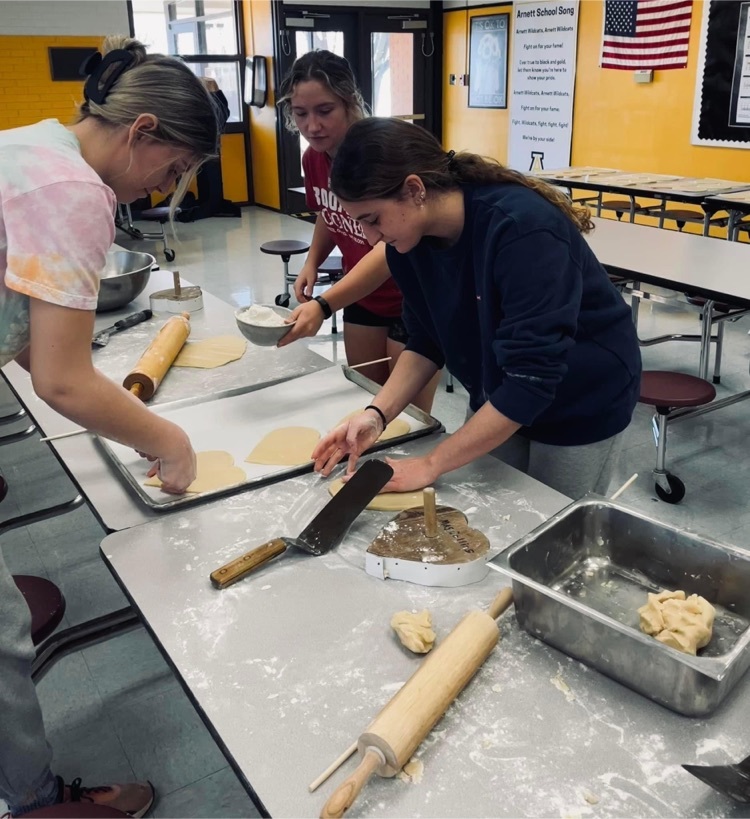 Senior Beta club members, Anna Hope Sant'Anna, Sara Wayland, and Almudena Velez, cutting out Valentine's cookies